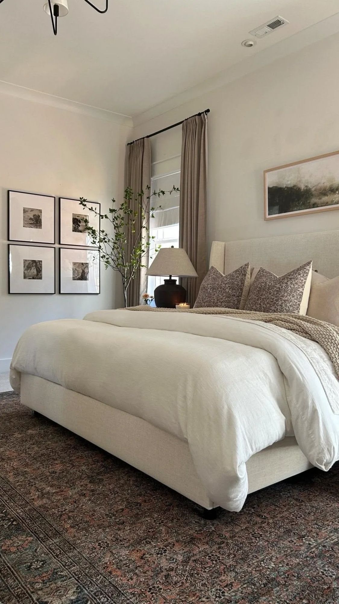 Serene bedroom with a linen upholstered bed, framed botanical prints and a vintage rug