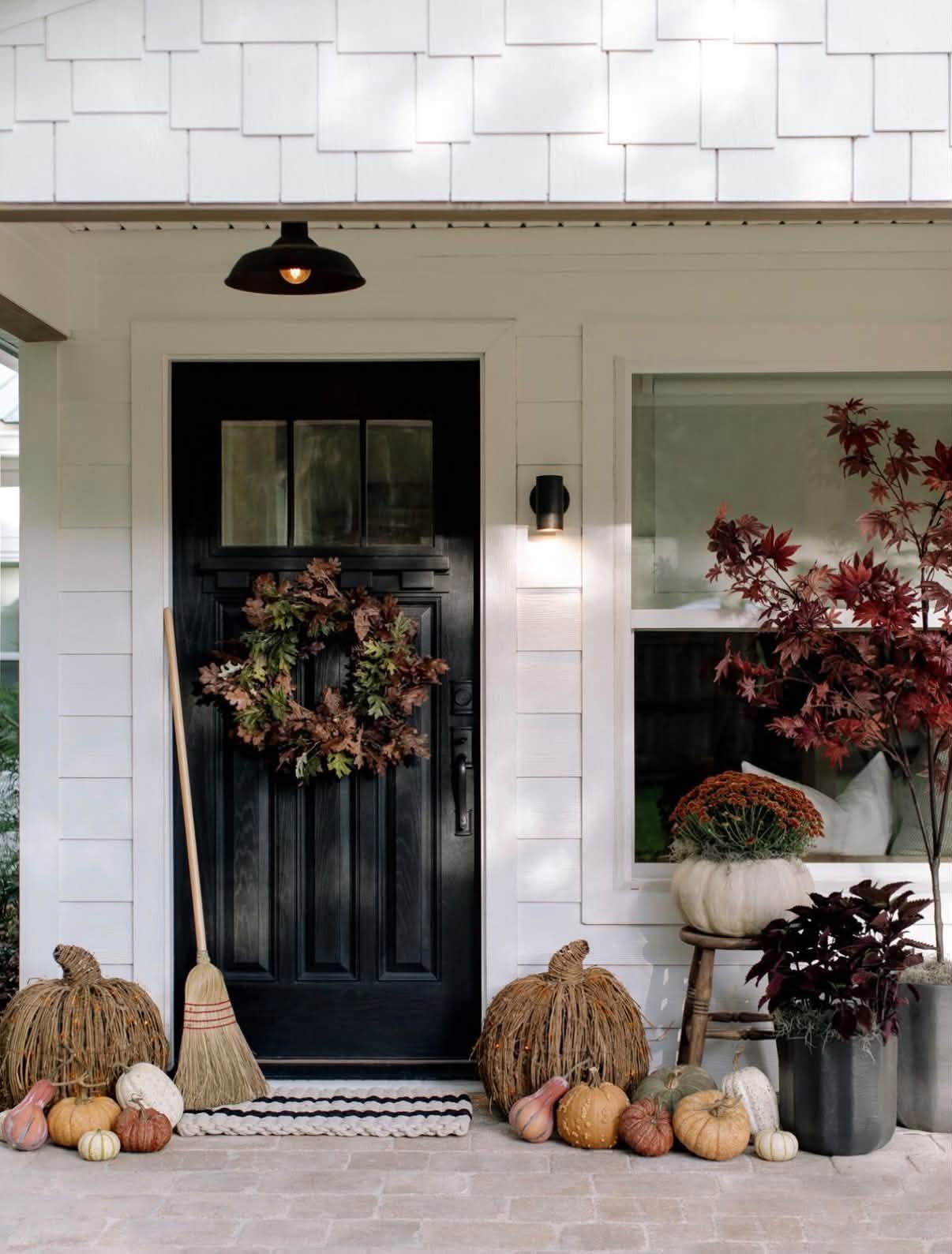 Cottage front porch with an oak leaf wreath, twig pumpkins, gourds and a red maple