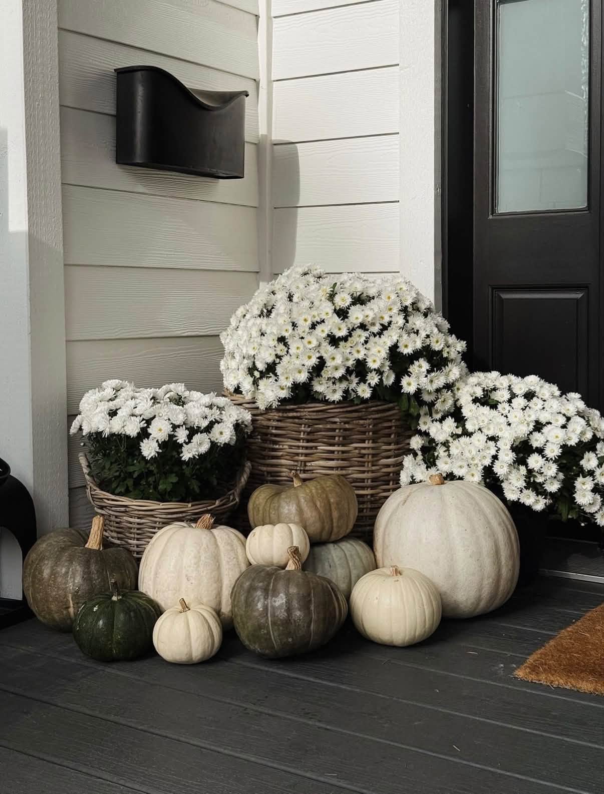 Porch corner with white mums in wicker baskets and heirloom pumpkins