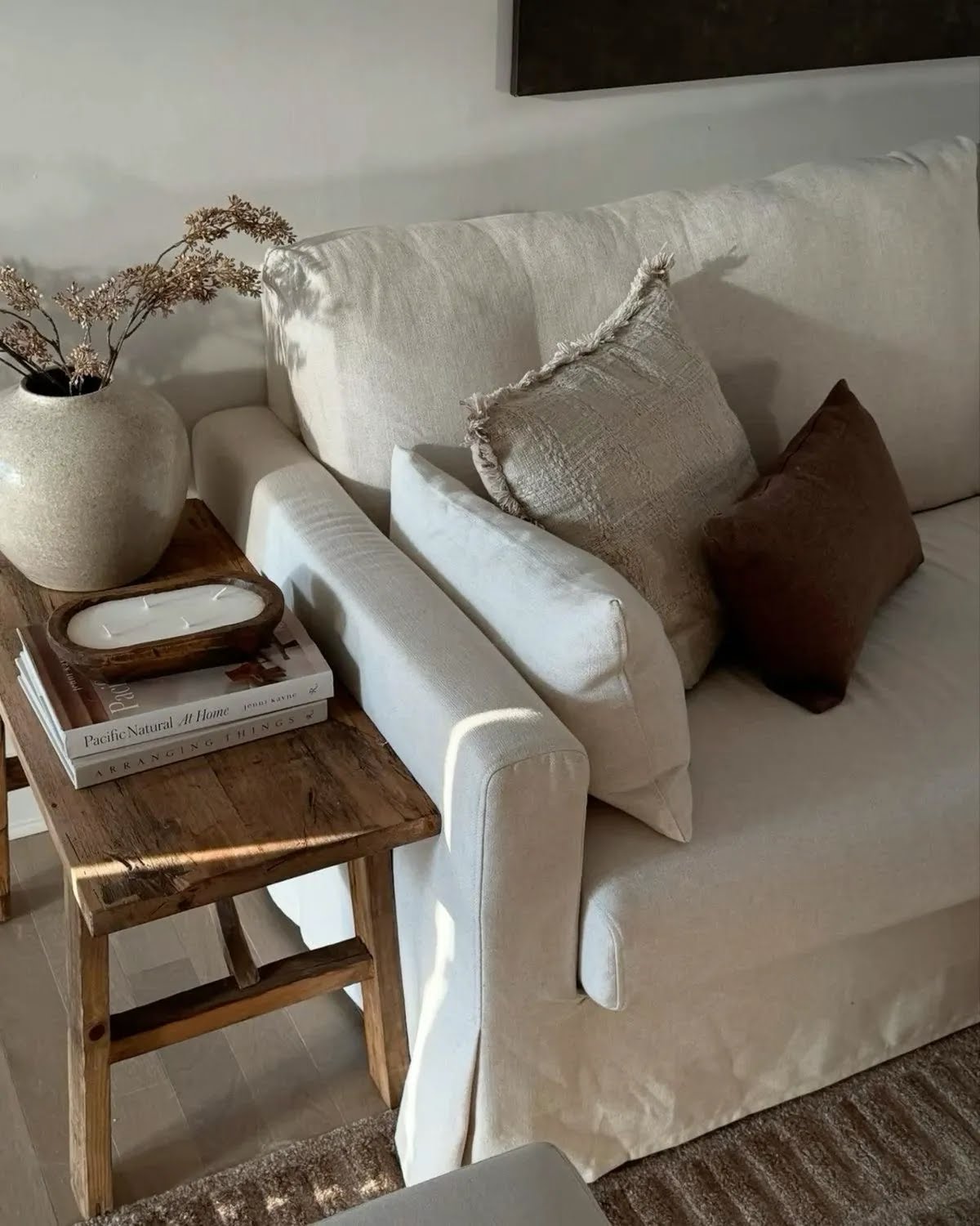 Linen sofa styled with textured pillows and a rustic side table